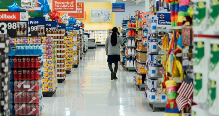 Person walking down store aisle featuring household goods.