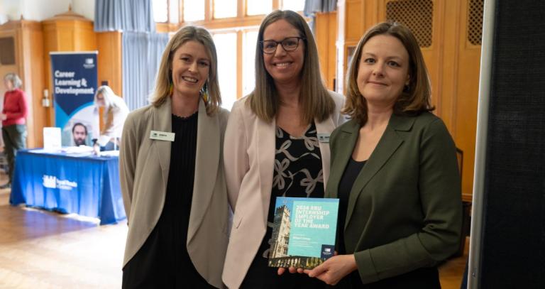 Robyn Booth, Heather McDonald and Ali Spillette standing together with career fair booths in the background.