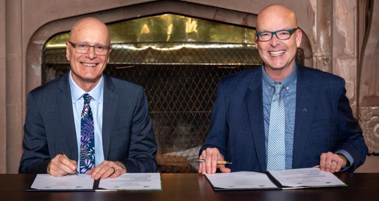 Philip Steenkamp and Tim Rahilly seated at a desk, signing a memorandum of understanding.
