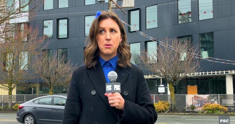 A TV reporter stands in front of the new West Shore collaborative campus building