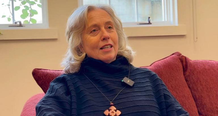 A woman sits on a red couch in front of a window