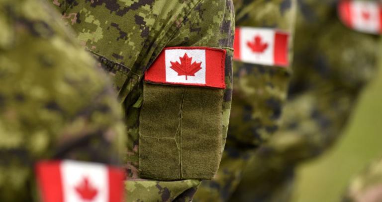 Small embroidered Canadian flag badges on the left sleeve of green military fatigues
