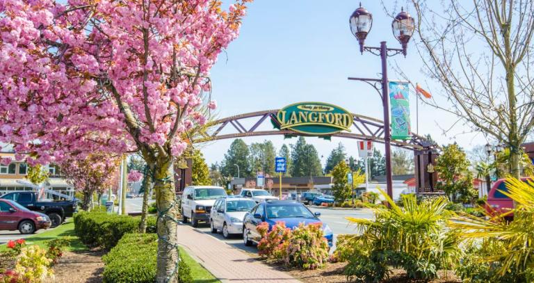 City of Langford welcome sign, with a blossoming cherry tree on the road beside it.