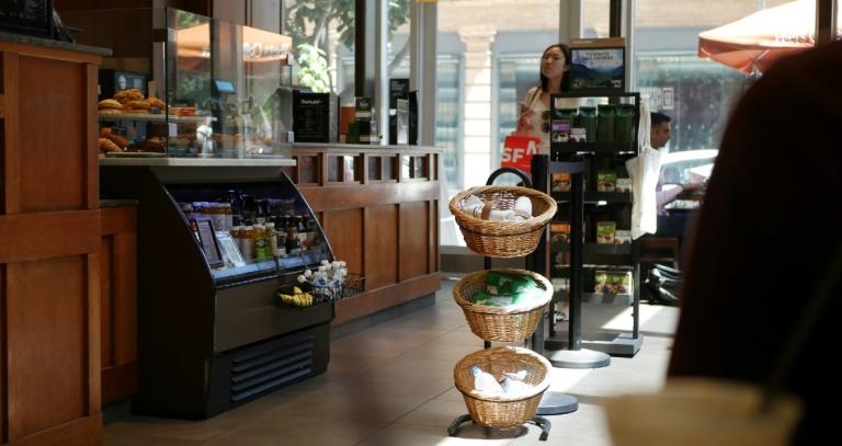 Cafe with coolers and grab and go items, a woman is looking at the food options.