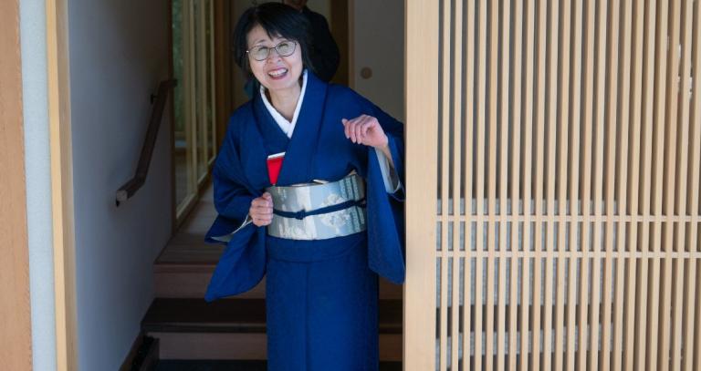 Urasenke Tankōkai Victoria Association member standing in the doorway of the Royal Roads Teahouse smiling and inviting visitors in.