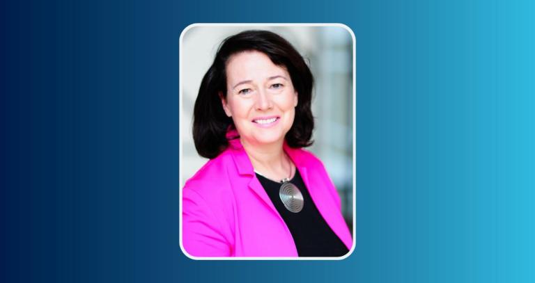 The Honourable Janet Austin smiling in front of an urban background.