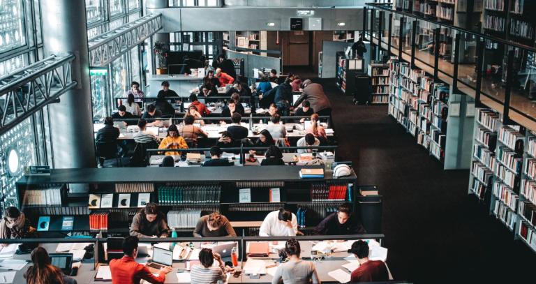 A modern library in a university setting with students at tables studying