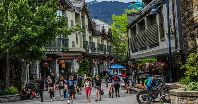 Whistler Village in summer with tourists walking along the streets in summer attire.