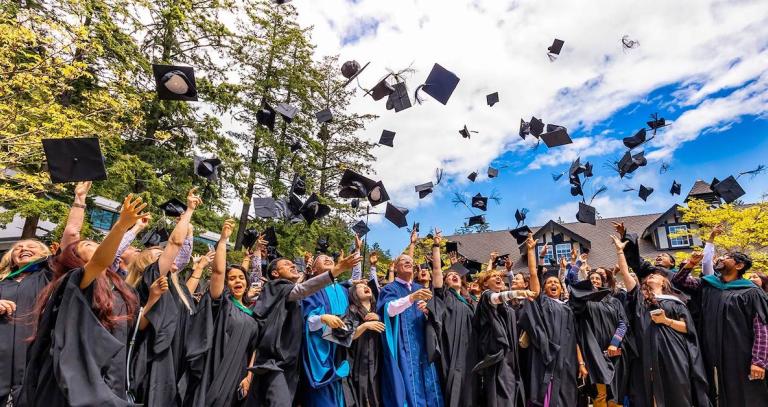 New grads toss their caps into the bright blue sky