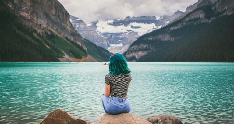 Woman sitting on a rock gazing out over Lake Louise.