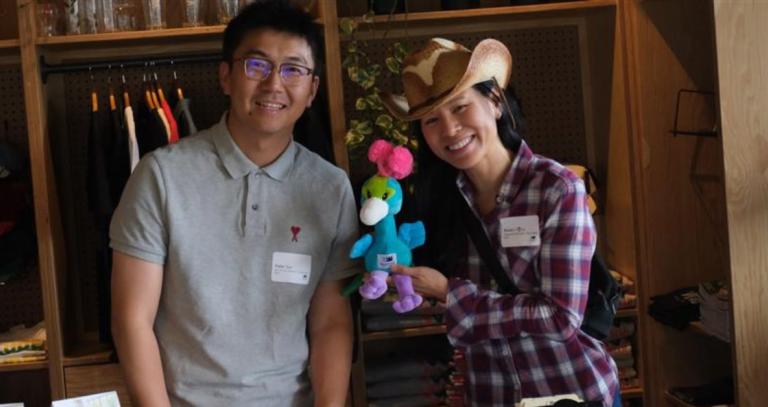 Two Royal Roads staff members standing with a peacock stuffie