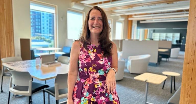 A woman smiles while standing in a library.
