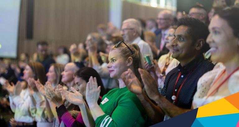 A crowd of people cheering at TEDxRRU