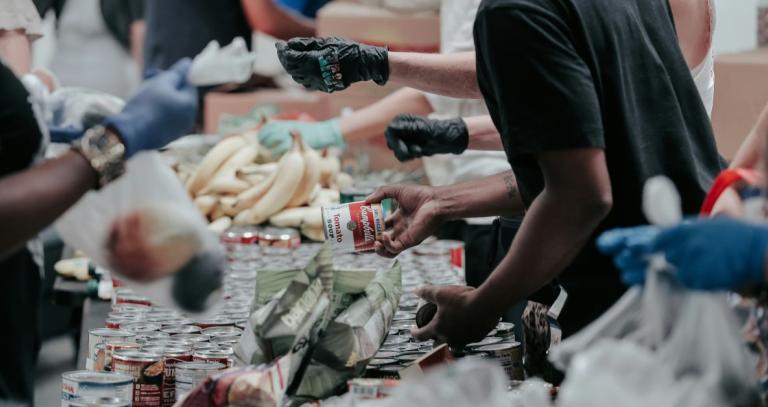 Volunteers at a food bank organizing a table full of cans 