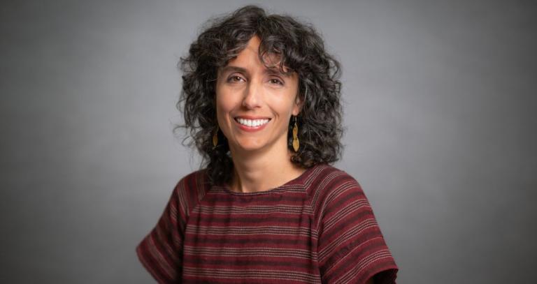 Melinda Quintero smiles in front of a photo backdrop. 