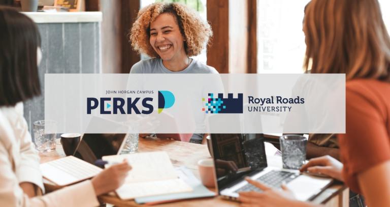 Three students laugh and work on laptops in a cafe
