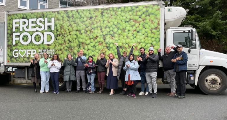 A group of people lined up in front of a big delivery truck