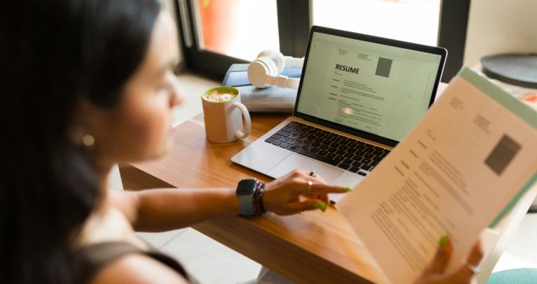 A young woman sitting in a cafe looking at a resume