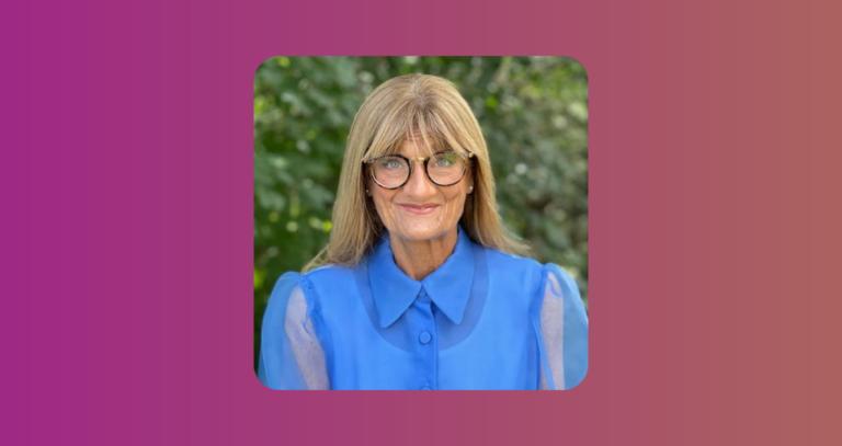 Kathy Cowan Sahadath wearing a blue blouse and dark-rimmed glasses.