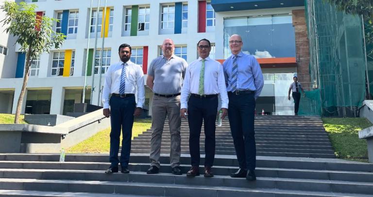 Four men stand on the steps of a building at the Sri Lanka Institute for Information Technology