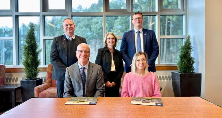 A group of executives from RRU and SD62 smiling at the signing of an MOU. 
