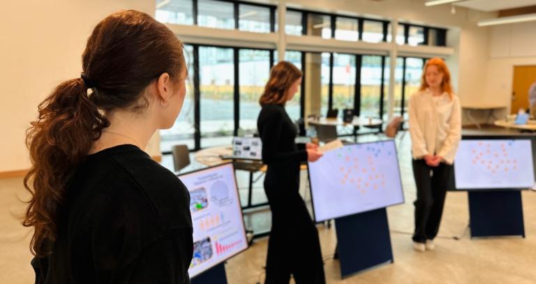 Three students presenting a "system map" inside the multi-purpose room at RRU John Horgan Campus