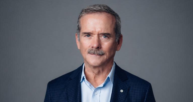 Chris Hadfield smiling in front of a neutral background