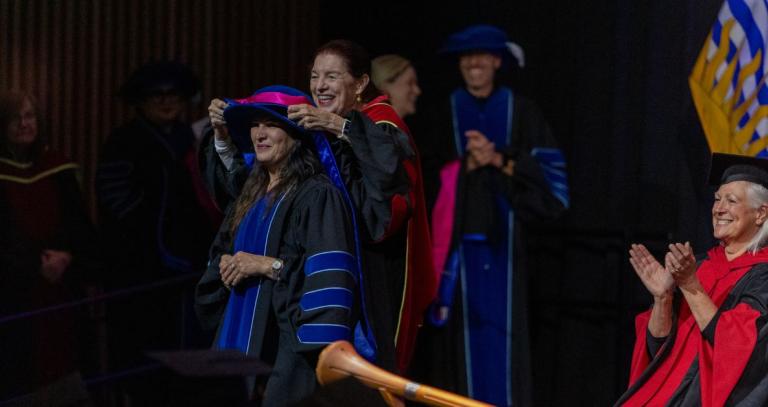 A doctoral graduate receives her sash on the convocation stage.