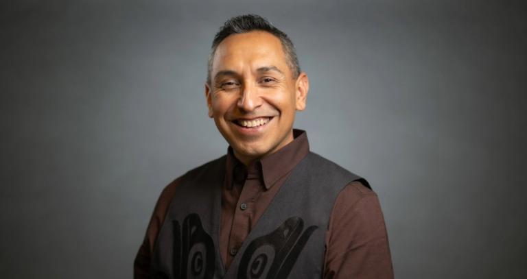 Rocky James smiles in front of a neutral background
