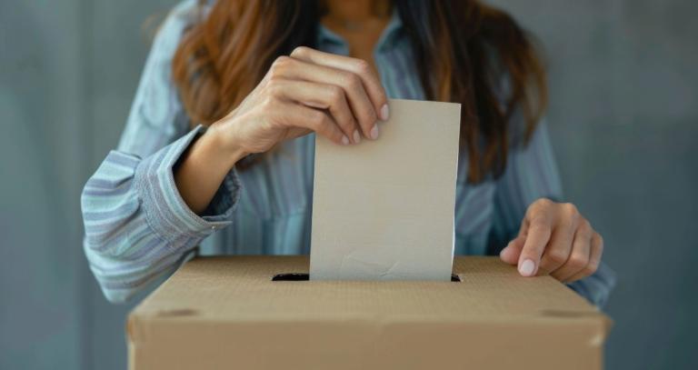 A woman puts a ballot in a voting box