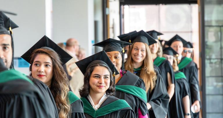 RRU graduates in regalia line up in the hallways to celebrate Convocation
