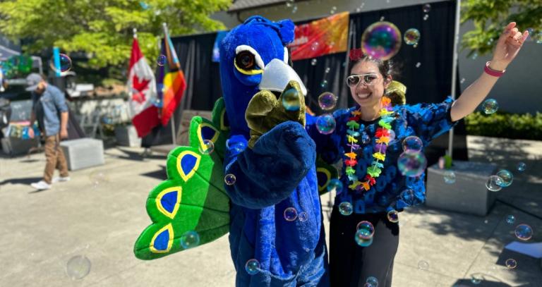 A student dances with someone in a peacock costume