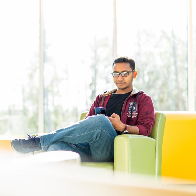 Student sitting in bright green chair, with yellow