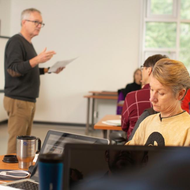 Instructor-holding-paper-and-speaking-to-class