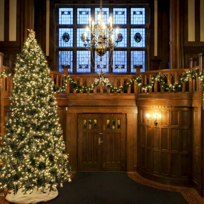 The entrance to Hatley Castle aglow with a tree, candles and chandelier.