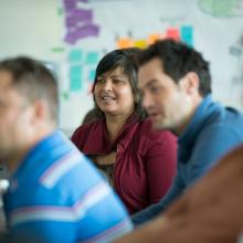 Three-students-in-class-with-whiteboard-and-sticky-notes-behind