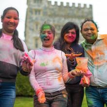 Four students outside covered in coloured chalk powder