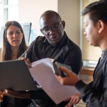 Three-students-looking-at-notes-and-laptop-together