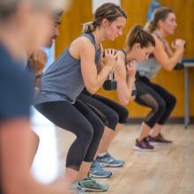 group-squatting-holding-weight-in-fitness-class