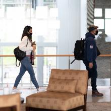 Two students walking with masks while social distancing