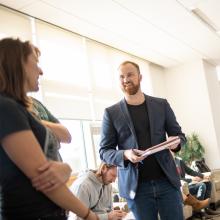 Two people standing and having a conversation in the student lounge.