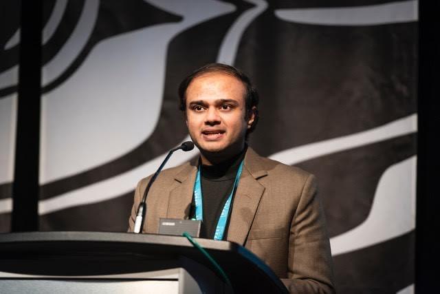 Agrim Banerjee speaks at a podium during the IMPACT Sustainability Travel and Tourism conference.